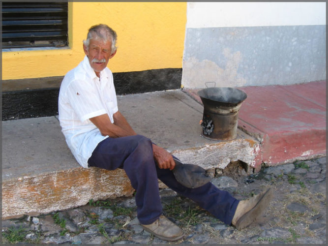 Man using a primitive wood stove to cook on the street in Ajijic, Mexico.