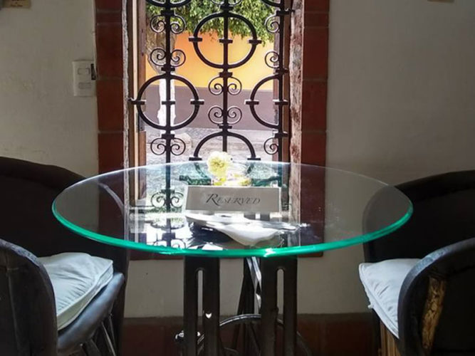 Glass table with reserved sign on it beside a wrought iron window looking out at the street at Teocintle Maiz restaurant in Ajijic.