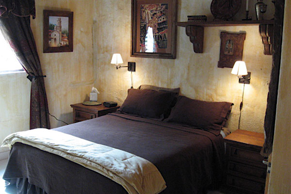 Bed in guest bedroom with wall lamps at Adobe Walls Inn Bed and Breakfast in Ajijic.