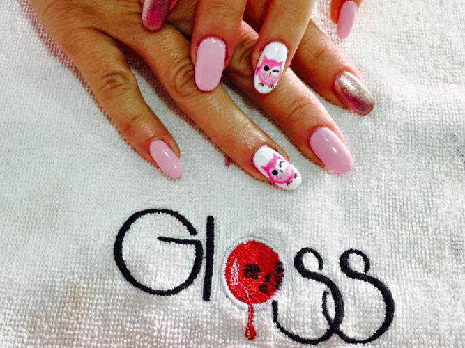 two ladies hands with pink manicured nails on a white towel with the word Gloss embroidered on it