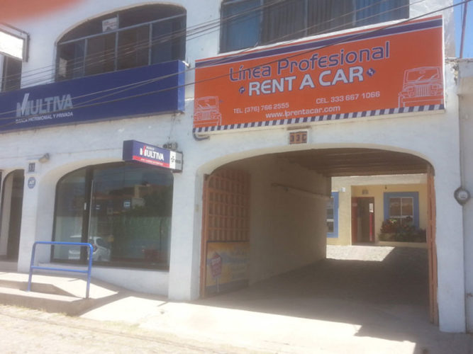 orange blue and white linea profesional rent a car sign above large archway entrance to building