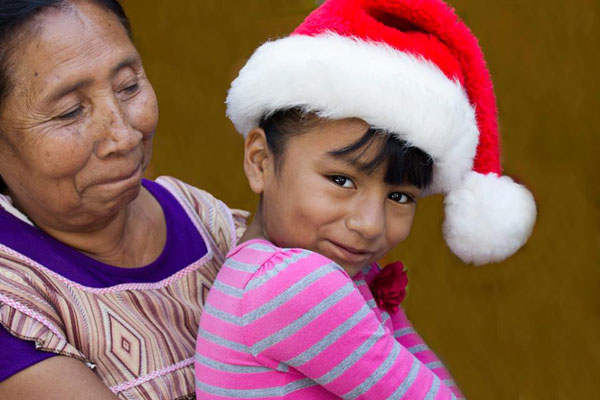 Little girl with Santa hat sitting on her grandmothers lap.