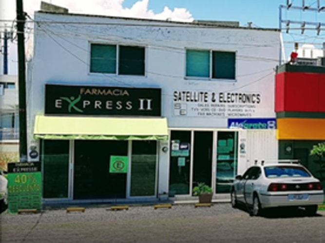 street view of farmacia express store with black white and yellow sign on white brick wall and open sliding glass doors 