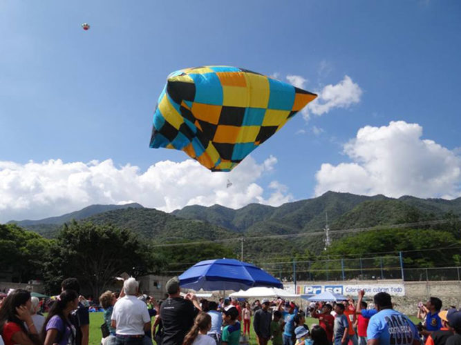 Colourful tissue paper globo floating in the air above field of spectators.