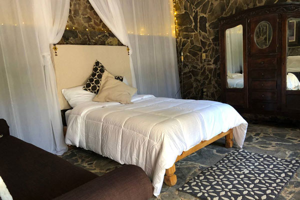 Guest bedroom with bed and flowing drapes in Casa Las Rocas Bed and Breakfast in Ajijic.