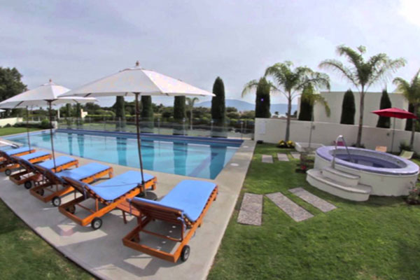 Pool area with lounge chair and umbrellas at Hotel del Pescador.