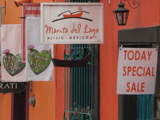 Various vinyl signs hanging from the outside wall of Manta del Lago in Ajijijc.