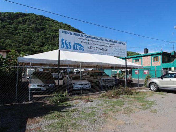 cars under tented canopy with s and s auto sign above