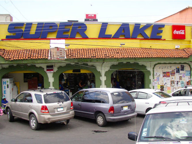 Super Lake storefront with bold blue letters, yellow walls, three open entrances to store and cars parked in front