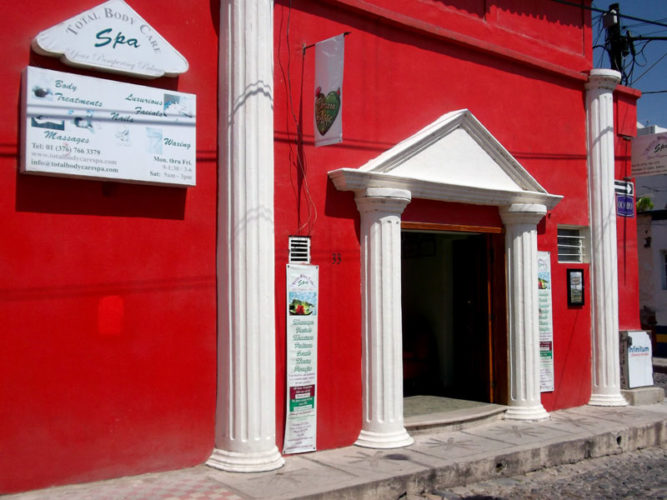 Total Body Care street front with red walls white columns and trimmed door way with promotional signs