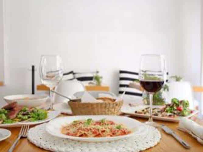 A newer Ajijic Restaurant with a plates of food of the table and mangia written on wall at Alex's Pasta Bar.
